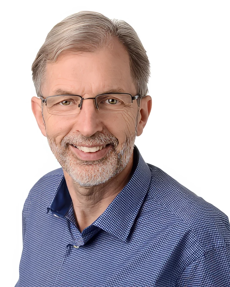 Portrait of Daniel Gut, a smiling middle-aged man with glasses wearing a blue checkered shirt.