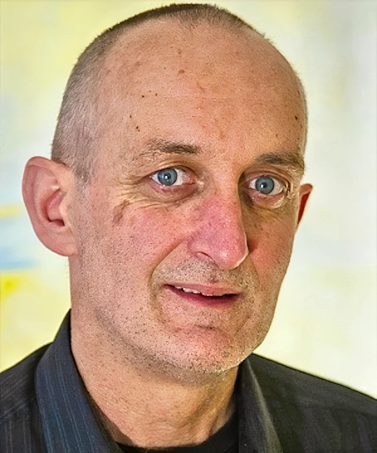 Close-up portrait of a middle-aged man with blue eyes and a shaved head